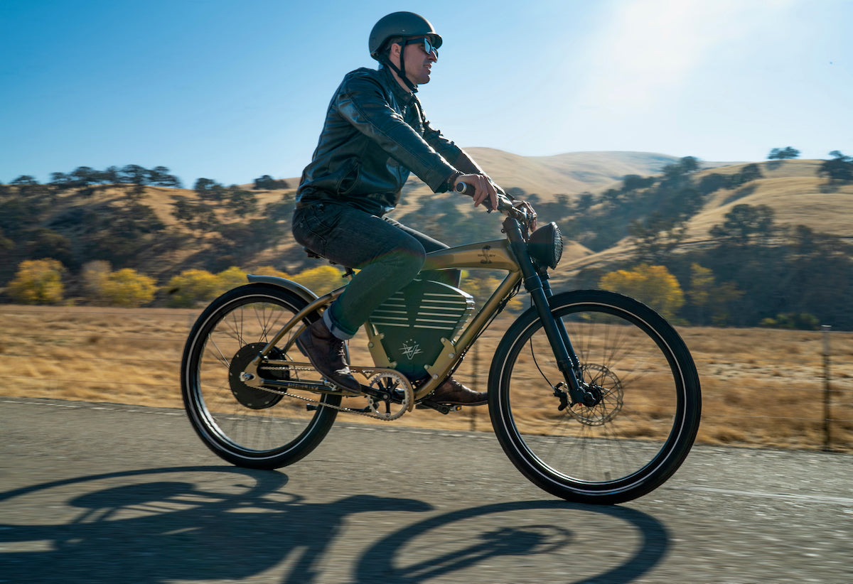 A helmeted rider on a green Shelby riding past open California hills