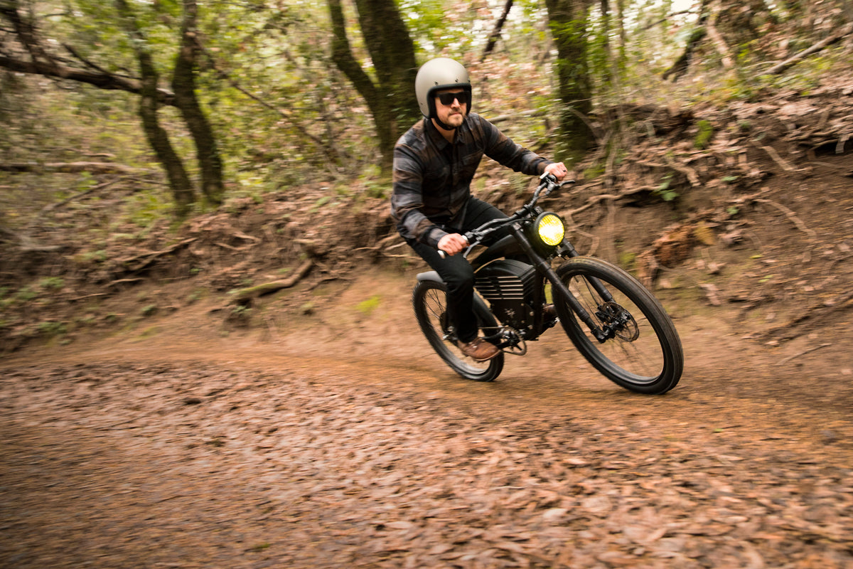 A helmeted Scrambler rider on a forest trail